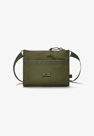 Bolsa de tela rectangular de color verde oliva, con un bolsillo frontal, cremallera superior, correa ajustable y un parche de logo en la parte delantera. Material resistente.