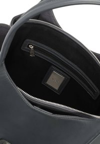 Interno della borsa in pelle di colore grigio scuro con un comparto con cerniera e una fodera nera liscia. Presenta un'etichetta del marchio e un stitching a contrasto.