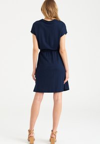 Vestido de manga corta azul marino con cintura ajustada, textura suave y una ligera forma en A, que presenta un escote redondeado y un dobladillo a media longitud.