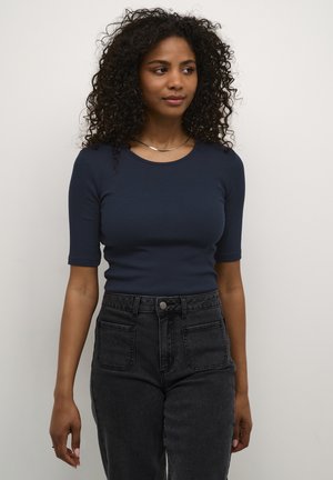 Navy blue ribbed short-sleeve top paired with high-waisted black jeans featuring front pockets and a button closure. Simple silver chain necklace.