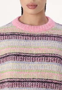 Sweter z teksturowanym splotem z poziomymi paskami w kolorze różowym, zielonym, czarnym i lawendowym. Okrągły dekolt, puszysty materiał i widoczne szwy.