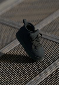 Svart mid-top sneakers med teksturert overdel, rund tå, snøring og en pull tab; har gummisåle og myk indre fôr.