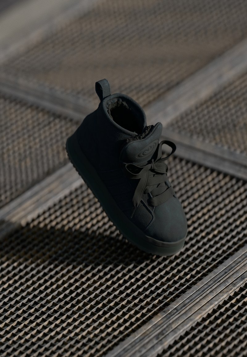 Svart mid-top sneakers med teksturert overdel, rund tå, snøring og en pull tab; har gummisåle og myk indre fôr.