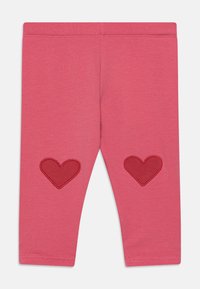 Rozā legingi ar gludu tekstūru, ar sarkaniem sirdspatēliem katrā ceļgalā. Elastīgs jostasvīrs komfortam un piemērotībai.