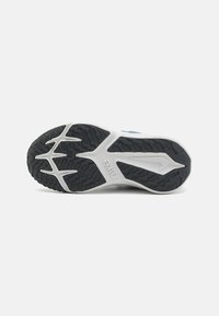 Nike tornacipő talp fekete gumiból, hullámos textúrával, fehér középtalppal és logóval. A tapadást biztosító mintázat jól látható.