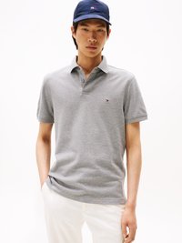 Grijze polo shirt van katoen met een drieknops sluiting, korte mouwen en een klein logo op de linkerkant van de borst. Gecombineerd met witte broek.