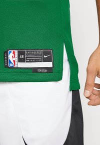 Zelený basketbalový dres s meshovou strukturou, štítem "Swingman", velikostní označení 48 a logem "Nike" na lemu. Bílé šortky s černými akcenty.