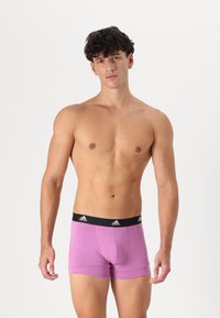 Rožinės medvilnės boxer tipo kelnaitės su juodu elastingu juosmeniu, kuris turi Adidas logotipą. Prigludęs dizainas su lygiu paviršiumi.