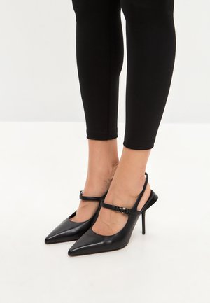 Décolleté neri in pelle con punta affusolata, cinturino alla caviglia e tacco a stiletto. Texture liscia con minimi dettagli in metallo.