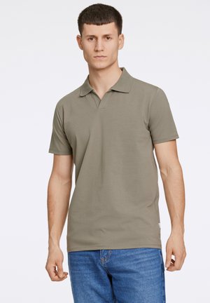 Olive green polo shirt with a traditional collar and short sleeves, made from a smooth cotton blend, paired with light blue denim jeans.