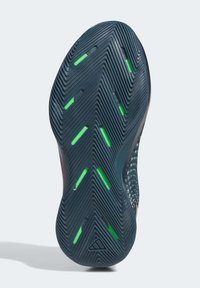 Shoe sole with deep grooves, dark blue rubber, and green rubber accents. Textured surface for grip and stability. Lightweight design.