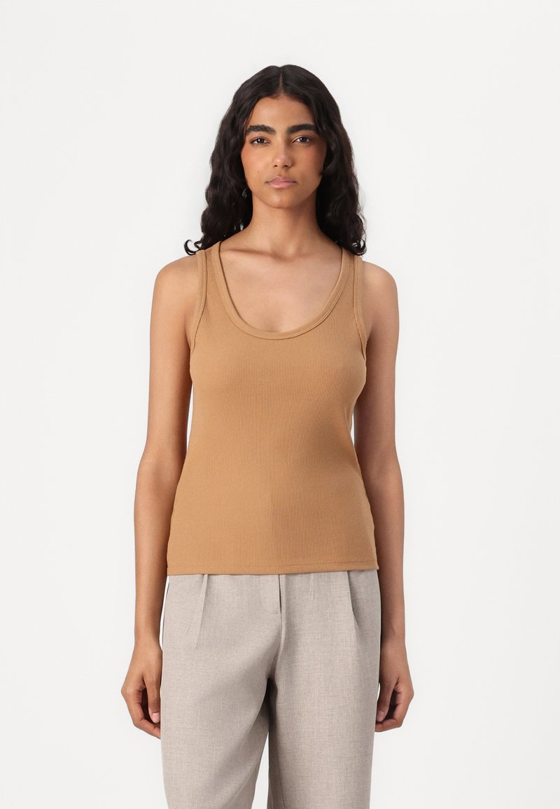 Camiseta de tirantes marrón con cuello ancho en forma de barco, diseño ajustado y textura suave, combinada con pantalones gris claro.