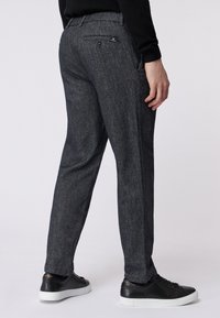 Szare spodnie o teksturowanej fakturze z dopasowanym krojem, z bocznymi i tylnymi kieszeniami, zestawione z czarnymi sneakery dla uzyskania casualowego wyglądu.