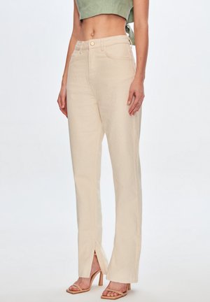 Pantalons large beige clair en tissu texturé, dotés d'une fermeture à bouton à l'avant et d'accents de fente sur le bas.