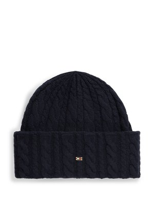 Bonnet en maille torsadée bleu marine avec revers plié et petite étiquette rectangulaire avec logo au centre avant du revers.