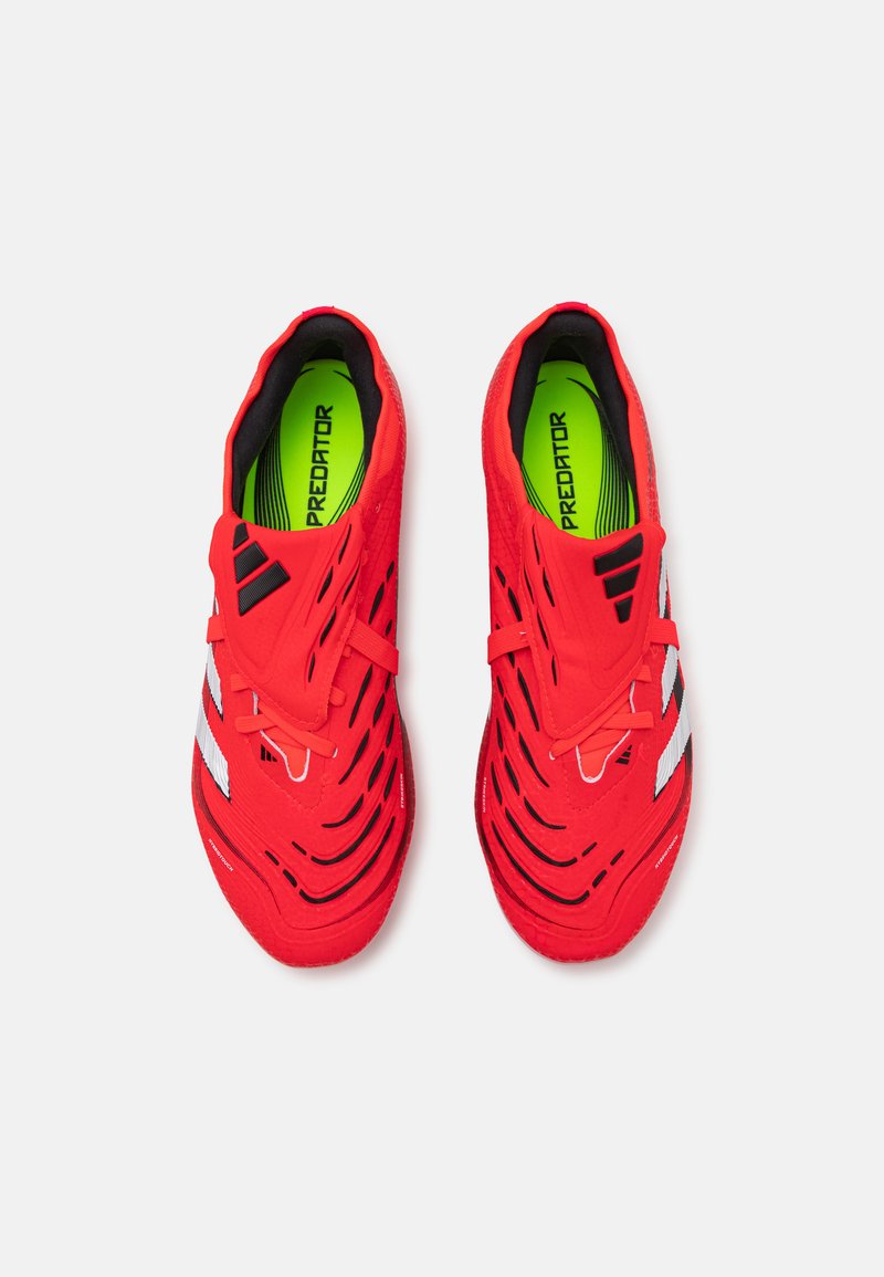Baskets de sport rouges avec une tige texturée, un design épuré et des accents blancs. L'intérieur possède une semelle intérieure vert vif avec un logo.