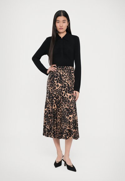 Sort skjorte med lange ærmer og krave, parret med en mellemlang nederdel med leopardmønster. Sorte højhælede sko fuldender outfittet.
