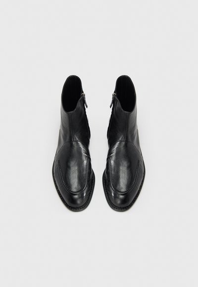Μαύρα δερμάτινα μποτάκια αστραγάλου με λεία υφή, στρογγυλεμένη μύτη, πλαϊνά φερμουάρ και αντίθετες ραφές κατά μήκος της άκρης.
