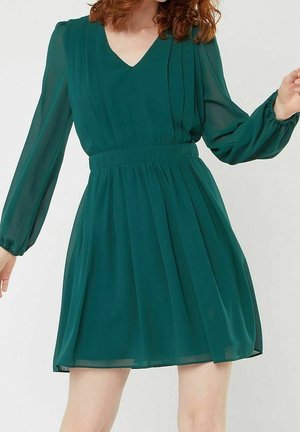Green chiffon dress with a V-neck, long puff sleeves, and pleated design. Features a fitted waist and flowy skirt that ends above the knee.