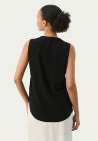 Top negro sin mangas con dobladillo redondeado y textura suave y lisa, diseñado con un corte relajado para mayor comodidad.