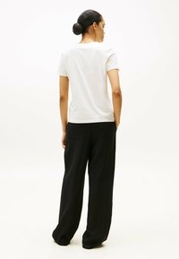 Camiseta blanca de algodón combinada con pantalones negros holgados. La camiseta tiene un corte clásico y los pantalones cuentan con bolsillos laterales y un ajuste relajado.
