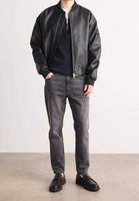 Svart fusk läder bomberjacka, grått tröja, grå jeans, svarta loafers; elegant design, slät textur och åtsittande silhuett.