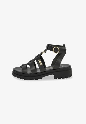 Sandalo in pelle nera con più cinturini verticali, un accent metallico circolare e una suola spessa e texturizzata. Include una cinghia regolabile per la caviglia.