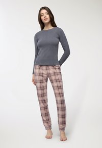 Maglietta a maniche lunghe di colore grigio scuro abbinata a pantaloni da pigiama a quadri rosa chiaro, con vita elastica e polsini.