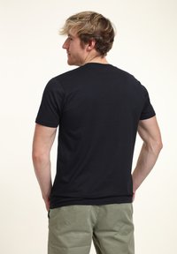 Svart kortärmad t-shirt med rundad halsringning, tillverkad av mjukt bomullstyg. Har rak nederkant, enkel design och inga synliga logotyper eller mönster.