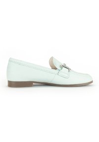 Lichtmintgroene leren instapper met een platte bruine zool en metalen accent met schenkingdetails. Zachte textuur met gestikte naden langs de randen.