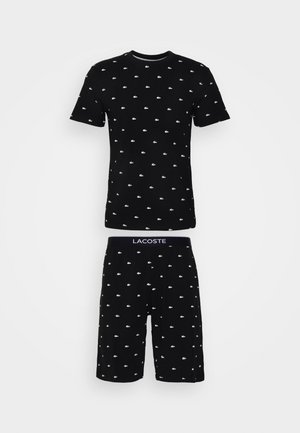 Zwart katoenen pyjama-set met een shirt met korte mouwen en shorts, beide met witte Lacoste-logo's in een herhalend patroon.