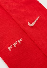 Punased spordisokid, mis on valmistatud kudumismaterjalist. Omavad valget Nike logo ja valget "FFF" teksti vastaspoolel.