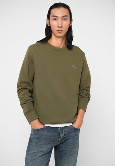 Sweatshirt vert olive, col rond, fabriqué en tissu doux. Présente un petit motif brodé sur la poitrine et des poignets côtelés.