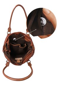 Borsa marrone in pelle aperta per mostrare l'interno e un localizzatore di sicurezza attaccato all'interno di una tasca con cerniera tenuta da una mano.