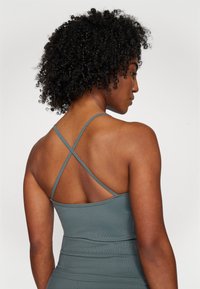 Gray ribbed tank top with thin crisscross straps, displaying a fitted design and smooth texture, highlighting the back view.