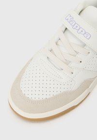 Baskets blanches avec une tige en cuir perforé, des accents en suède gris et une sangle Velcro. Comprend une semelle en caoutchouc et des détails cousus.