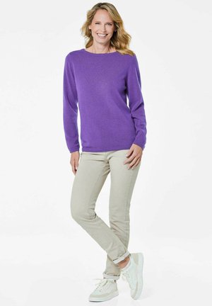 Paarse gebreide trui met lange mouwen en een ronde halslijn. Gecombineerd met lichtbeige, strakke broek en witte sneakers. Soepele textuur, casual stijl.