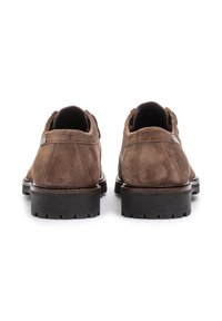 Scarpe in suede marrone con profilo basso, punta rotonda e superficie texturizzata, dotate di una robusta suola in gomma nera e dettagli minimalisti.