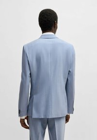 Ljusblå kavaj i en mjuk textur, subtila vertikala ränder, slim fit, enkel slits bak och tvåknappsstängning.