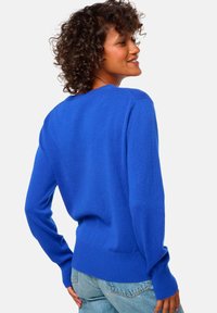 Un pull bleu vif en tissu doux, avec un col rond, des manches longues et des poignets et un ourlet côtelés pour un ajustement confortable.