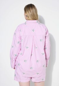 Set di camicia a righe rosa e pantaloni corti con ricami floreali. Presenta maniche lunghe, una vestibilità rilassata e una piega sul retro per un comfort aggiuntivo.