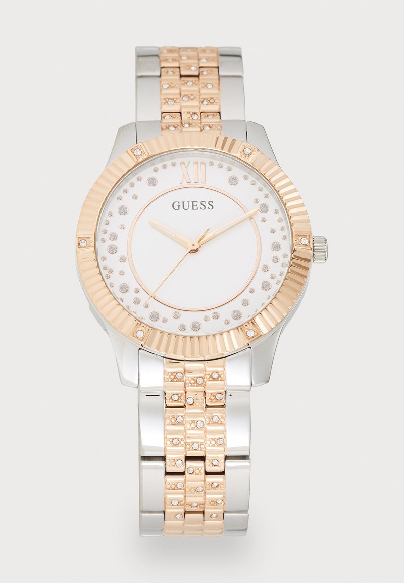 Ezüst és rózsaarany óra texturált lünettával, fehér számlappal, kristály díszítésekkel és láncos karkötő dizájnnal. Kvarchajtással rendelkezik.