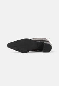 Suela de zapato de cuero negro con un patrón texturizado y estriado. Presenta un tacón moderado y bordes suaves. Diseño limpio sin acentos adicionales.