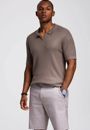 Light brown ribbed polo shirt with a collar, paired with light gray shorts, showcasing a subtle texture and a relaxed fit.