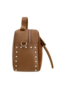 Bolso de cuero marrón con forma cuadrada, tachuelas plateadas en un lado, cierre de cremallera en la parte superior y un pequeño asa para llevar.