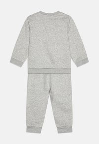 Ensemble en sweat-shirt et pantalon gris, fabriqué à partir d'un tissu doux. Présente des manches longues, des poignets côtelés et une taille élastique. Couleur uniforme et simple.