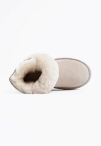 Chausson en suède beige clair avec une doublure en fausse fourrure crème douce et une ouverture arrondie, doté d'une semelle flexible et de détails de couture minimalistes.