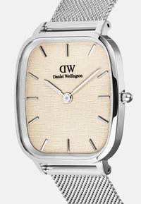 Orologio quadrato in acciaio inossidabile argentato con quadrante beige testurizzato, indici delle ore argentati e cinturino a maglia. Nome del marchio visualizzato sul quadrante.