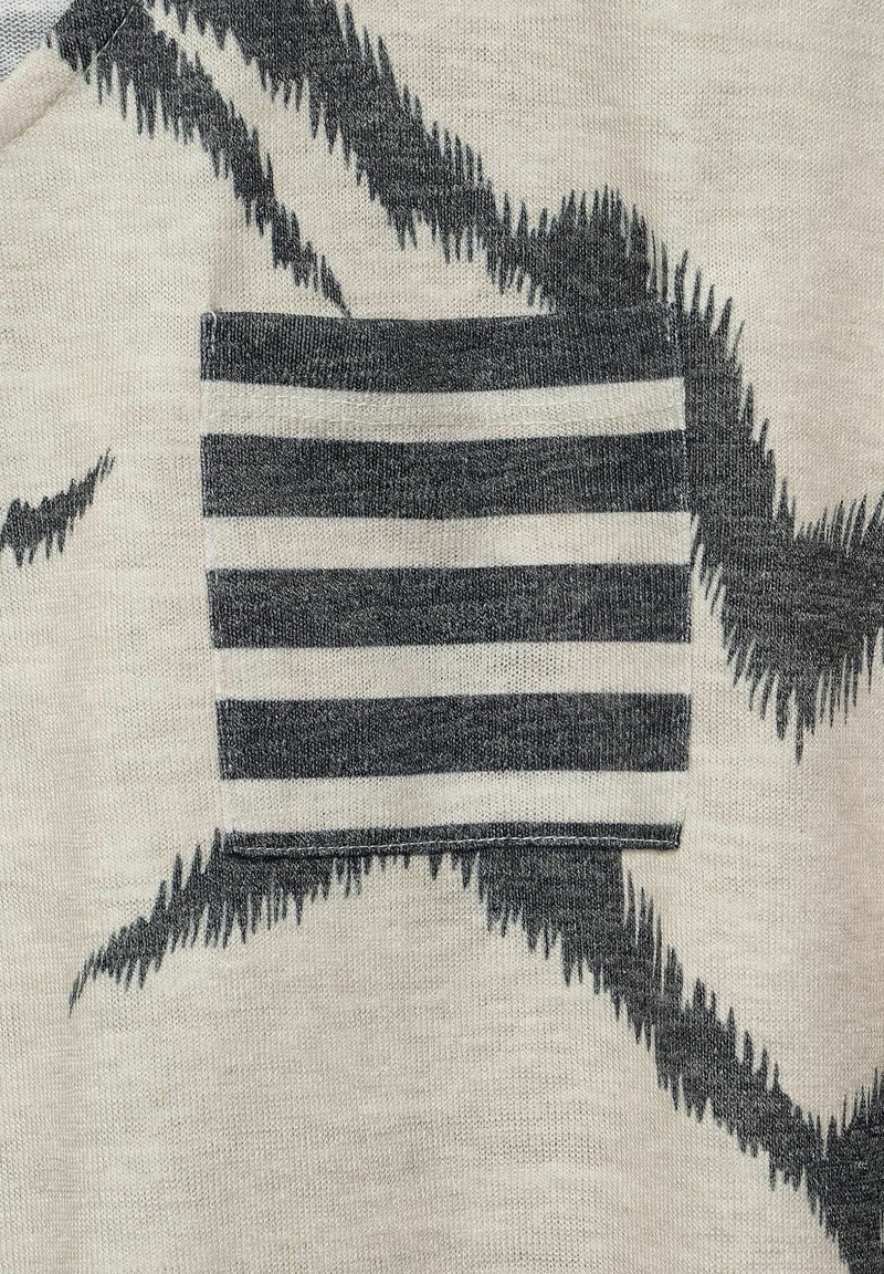 Knit garment with a light beige base and dark gray abstract patterns. Features a striped pocket in dark gray and white.