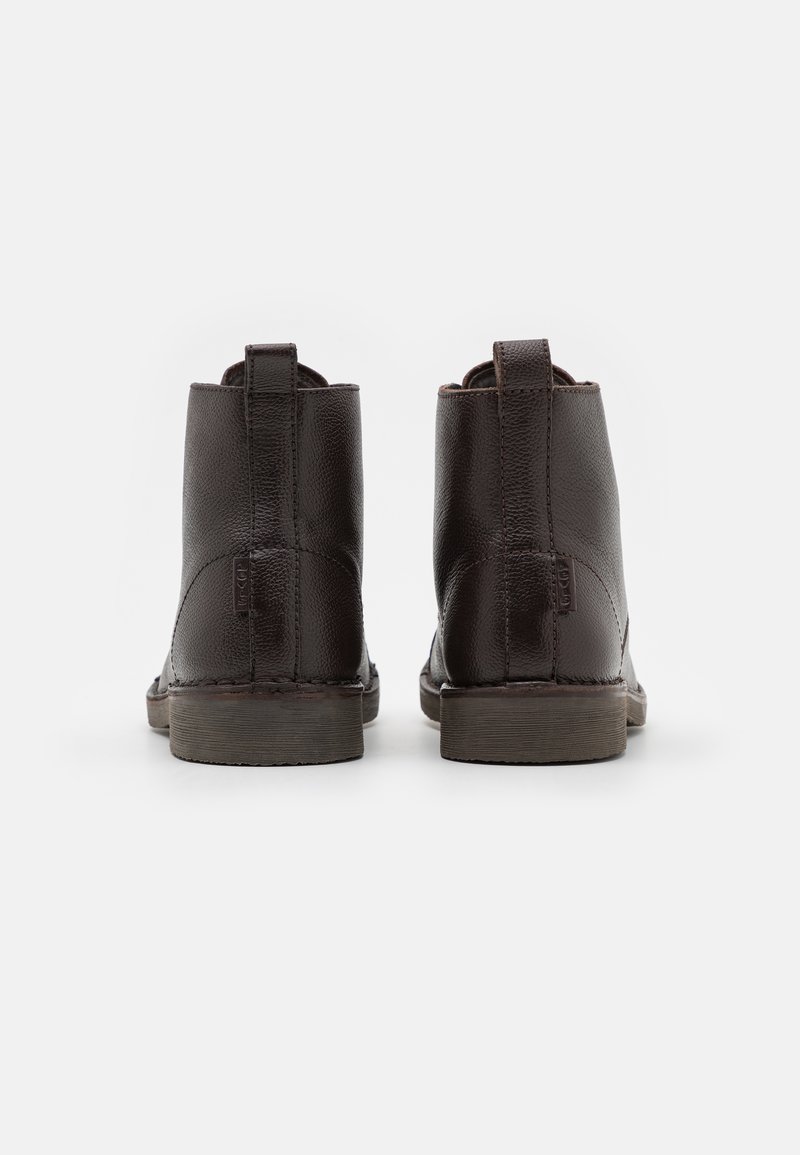 Botas de cuero marrón con un acabado suave, altura hasta el tobillo y una suela de goma resistente. Presentan pestañas para facilitar el calzado y un diseño con costuras mínimas.